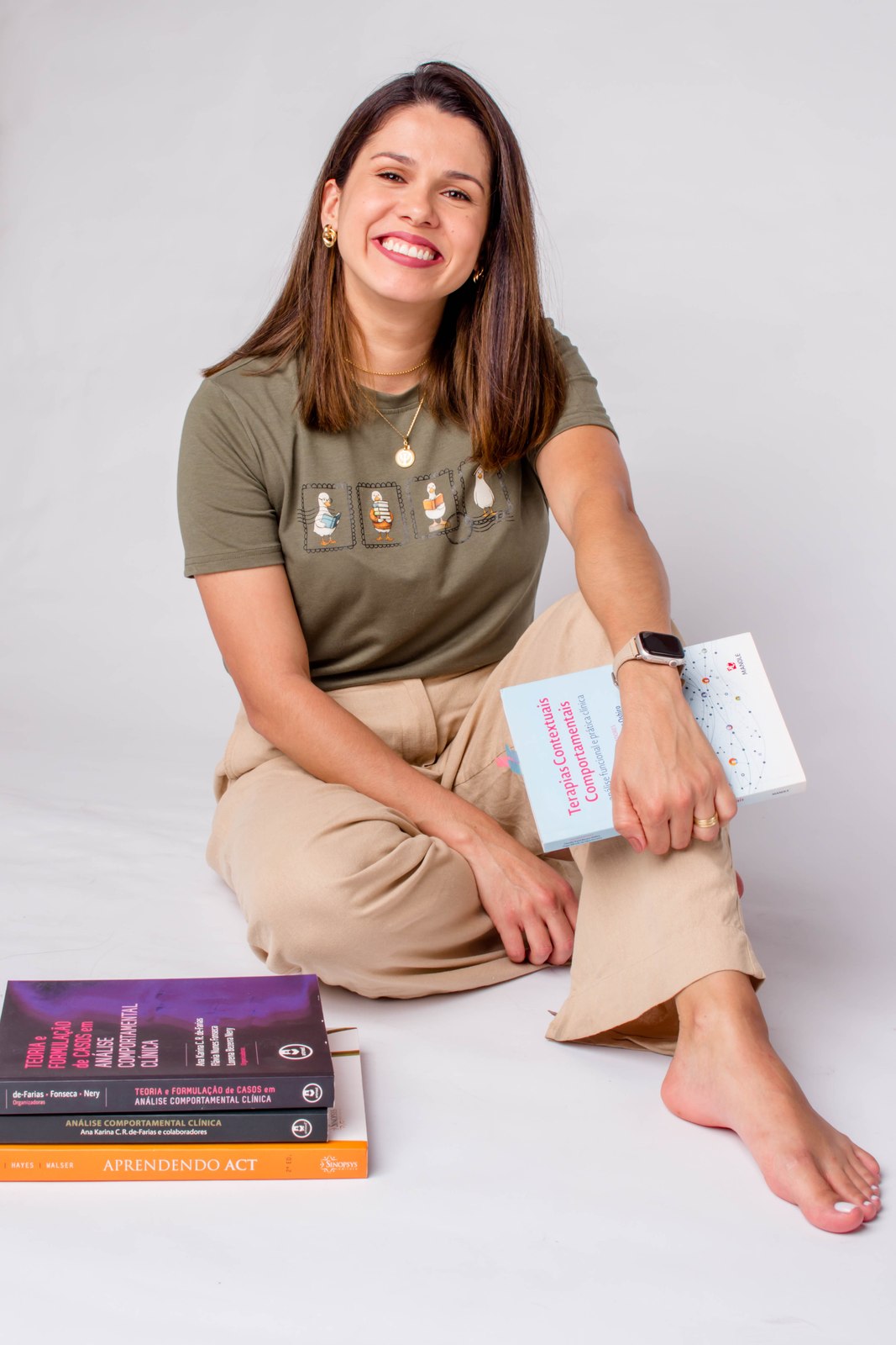 Daiane Lacerda sorrindo, segurando livros de psicologia